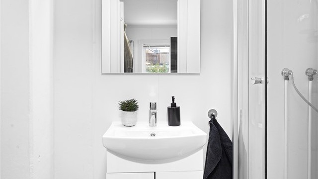 Badet er utstyrt med dusjkabinett, servant med underskap og gulvstående toalett.