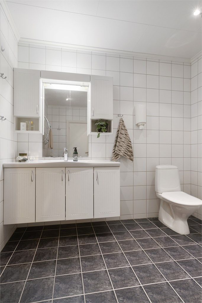 Badet har mørke gulvfliser kombinert med hvite flislagte vegger.