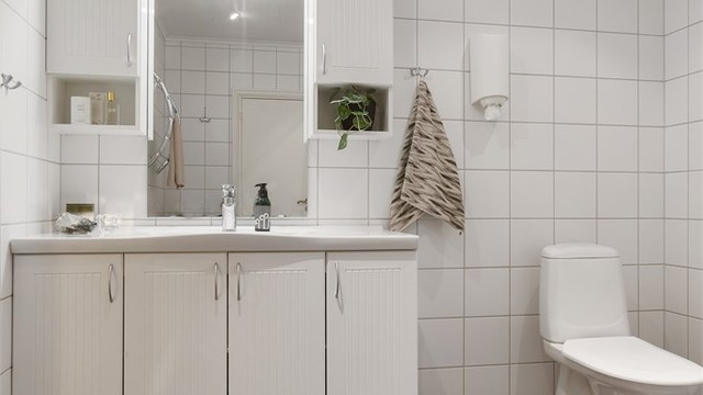 Badet har mørke gulvfliser kombinert med hvite flislagte vegger.