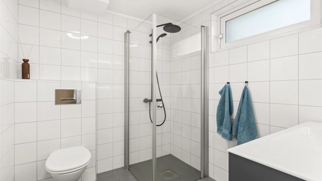 Flislagt bad med varmekabler, pusset opp i 2006. Dusjhjørne med innfellbare glassdører og sort dusjarmatur tilkoblet både hånddusj og regnfallsdusj