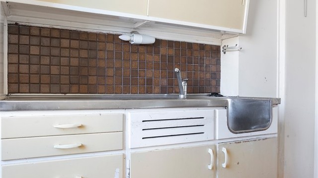 Kjøkkeninnredning fra byggeåret med benkeplate i rustfritt stål.