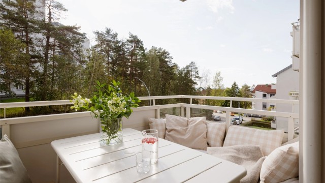 Den sydvendte balkongen på 7m² har blant annet en plassbygget sofa som utnytter plassen optimalt og herlig utsyn over tretoppene