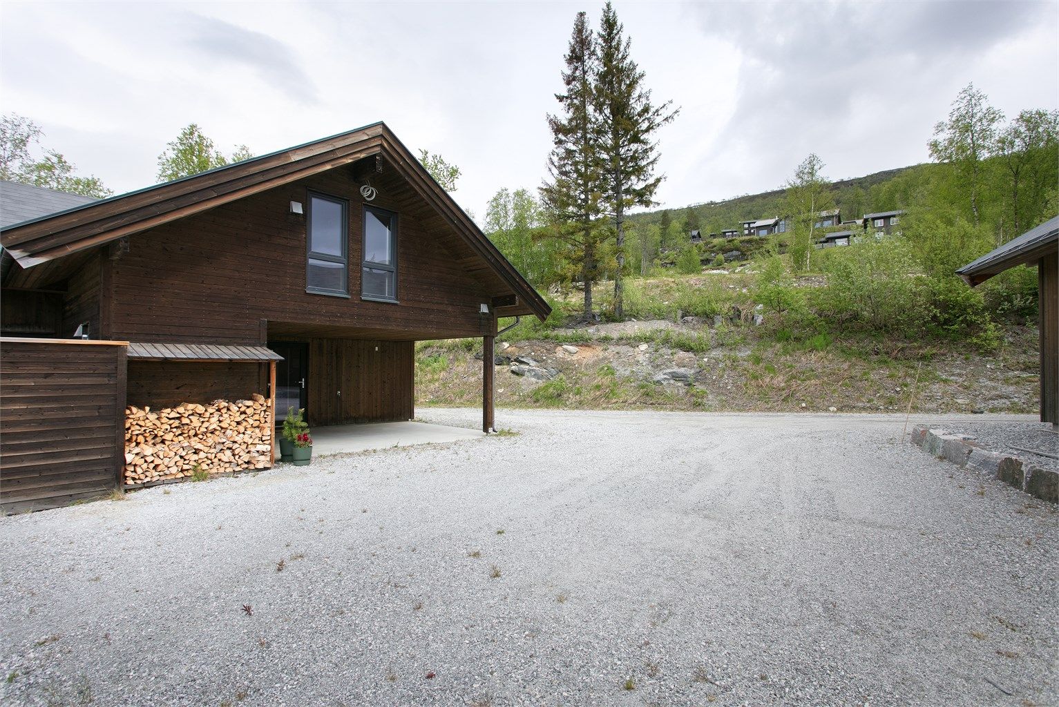 Gruset gårdsplass med gode parkeringsmuligheter rett utenfor hytta.