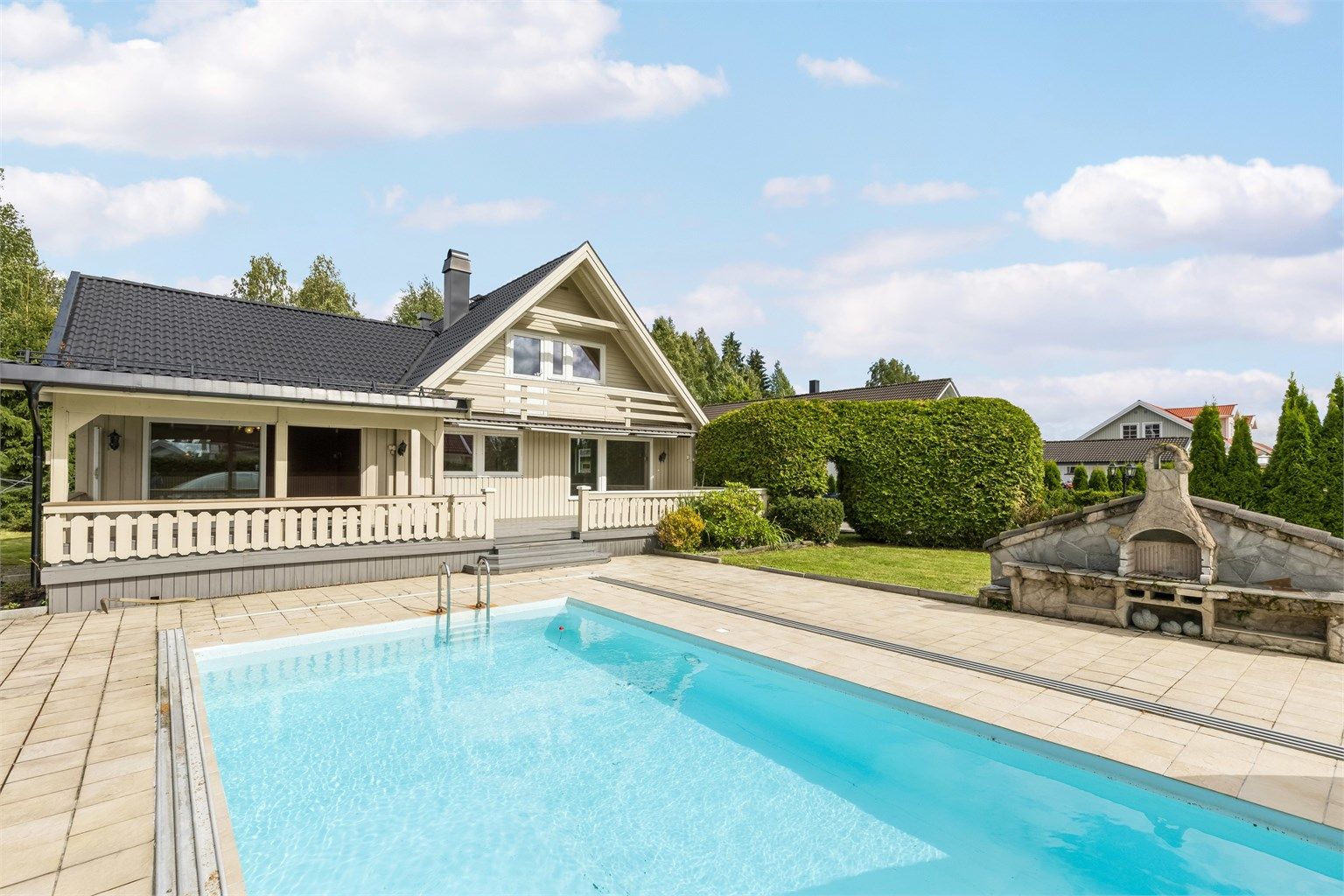 Flott uteplass med romslig delvis overbygd terrasse, svømmebasseng og hage