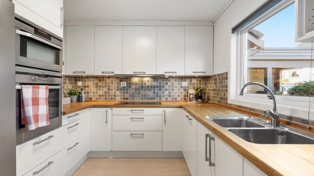 Tidløs og fin innredning fra 2008 i hvitt. Heltre benkeplate og spotter under overskap. Kjøkkenet har en praktisk og god utforming, som gir bra med oppbevaring i skuffer og skap, i tillegg til god benkeplass.