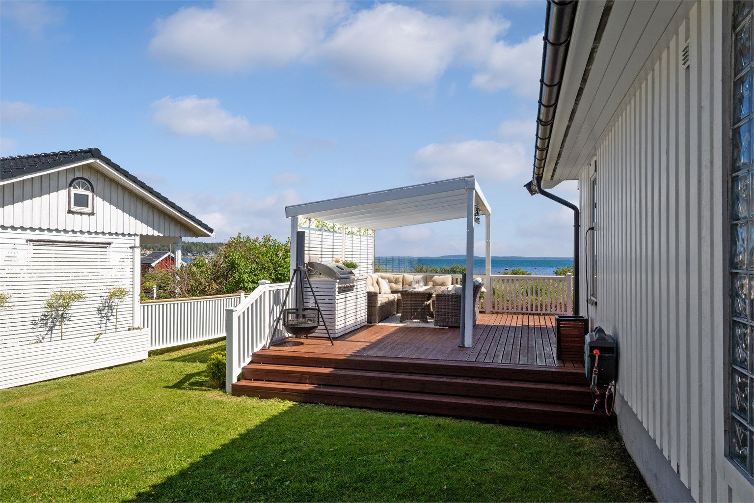 På nordvestsiden av verandaen er det bygd en pergola med tett, transparent tak, stort vindu mot utsikten, varmelamper og et plassbygd utekjøkken med grill i ytterste del. 