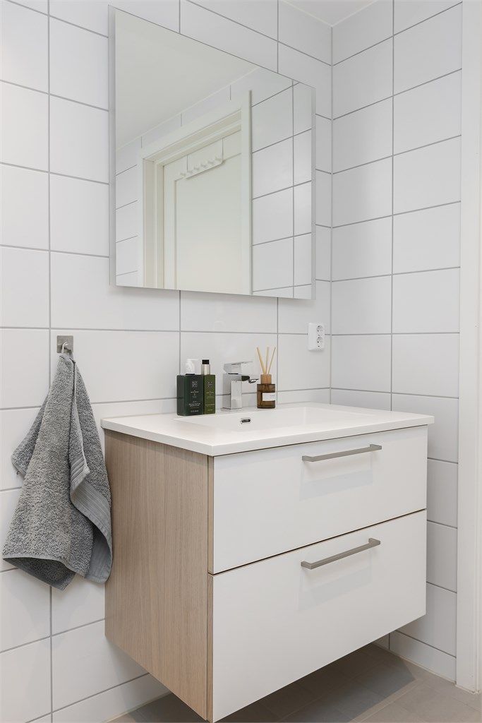 Badet har vegghengt toalett, servantinnredning og et dusjhjørne med regnfalls- og hånddusj.