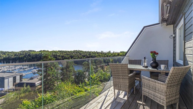 Balkongen har glassrekkverk, markise og god plass til sittegruppe.