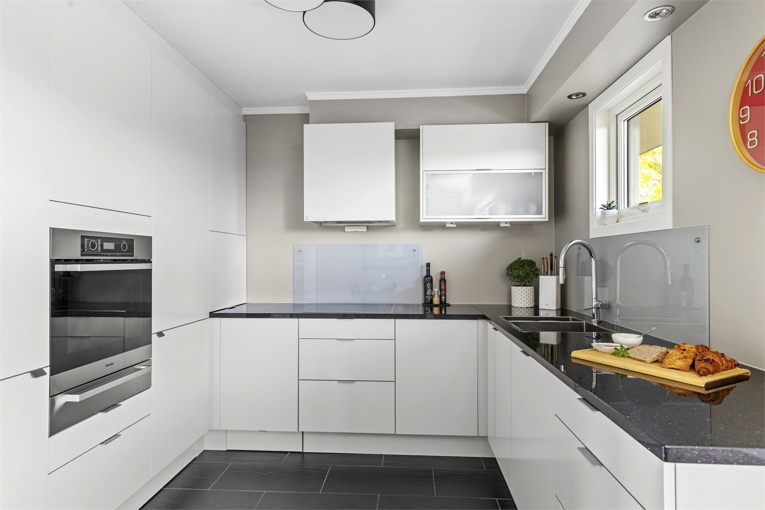 Kjøkkeninnredning fra HTH med benkeplate i stein og integrerte hvitevarer som medfølger.  Hvitevarer er levert av Miele og oppvaskmaskin fra Siemens.