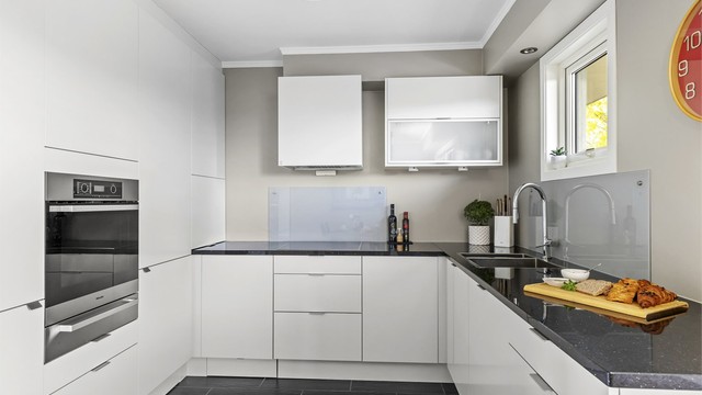 Kjøkkeninnredning fra HTH med benkeplate i stein og integrerte hvitevarer som medfølger. Hvitevarer er levert av Miele og oppvaskmaskin fra Siemens.