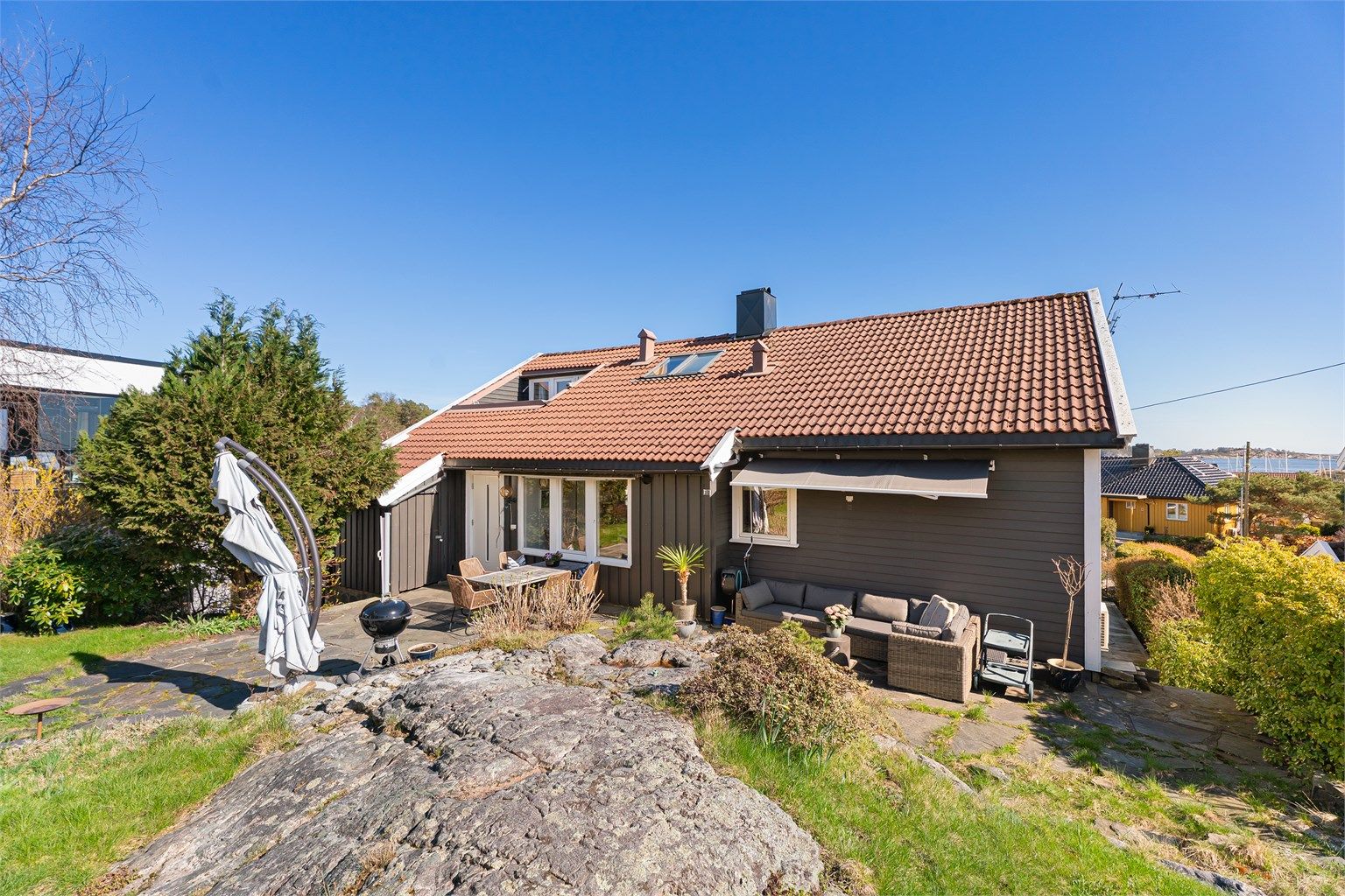 Boligens hage med plass til flere sittegrupper for sosiale sammenkomster