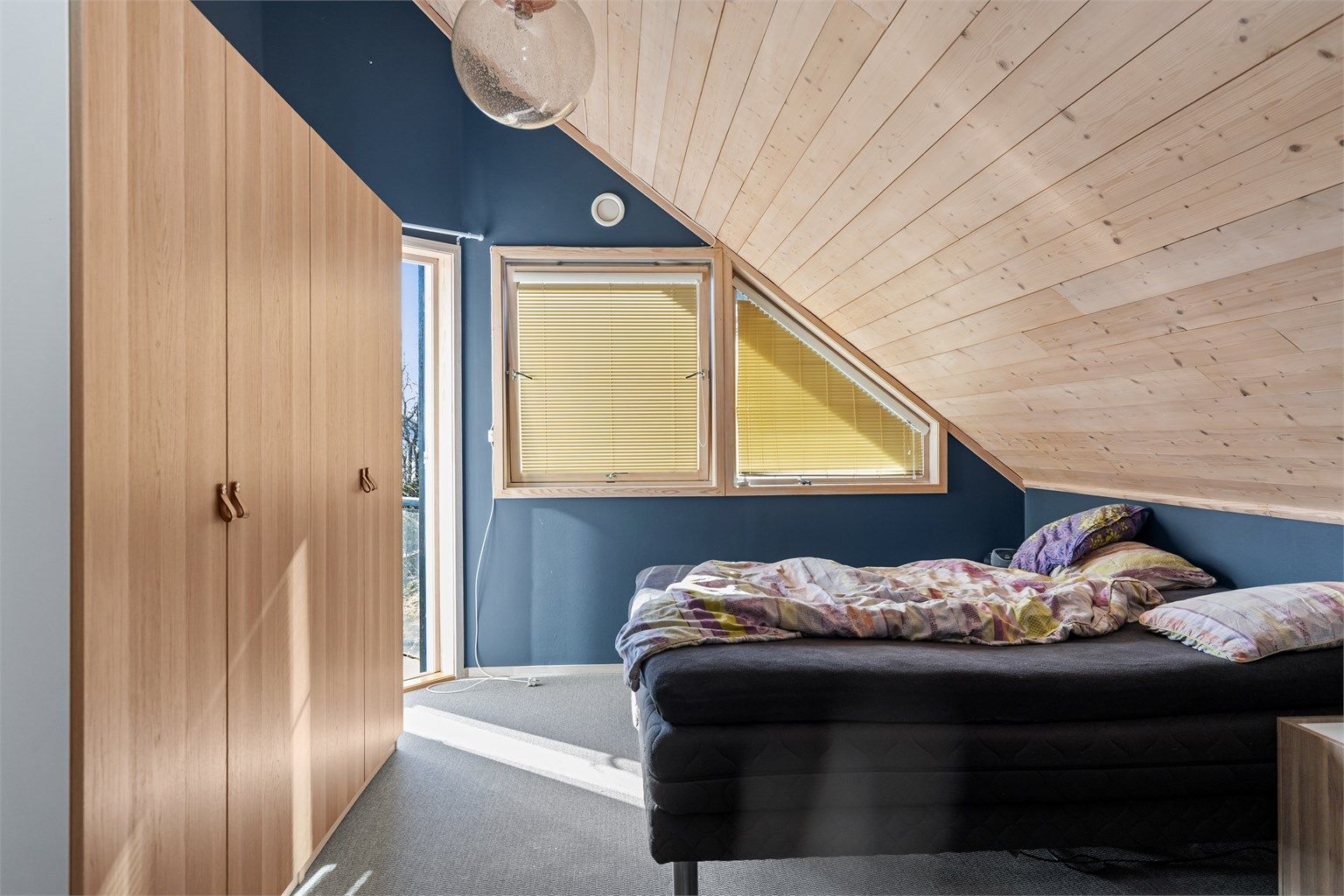 Det ene soverommet i andre etasje har teppegulv og utgang til en egen balkong på 2 m².