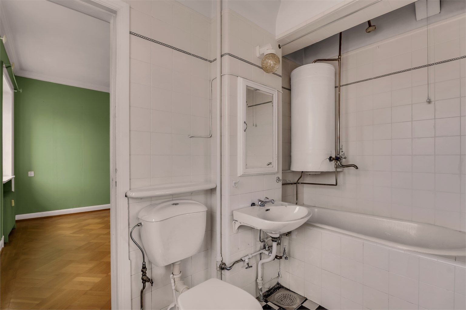 Eldre flislagt bad med toalett, servant og badekar. Badet er gitt TG 3.