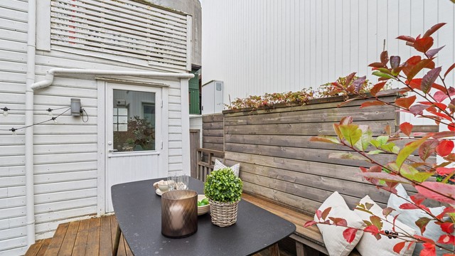 Plattingen ligger lunt til inntil husveggen og leveggen i tre.