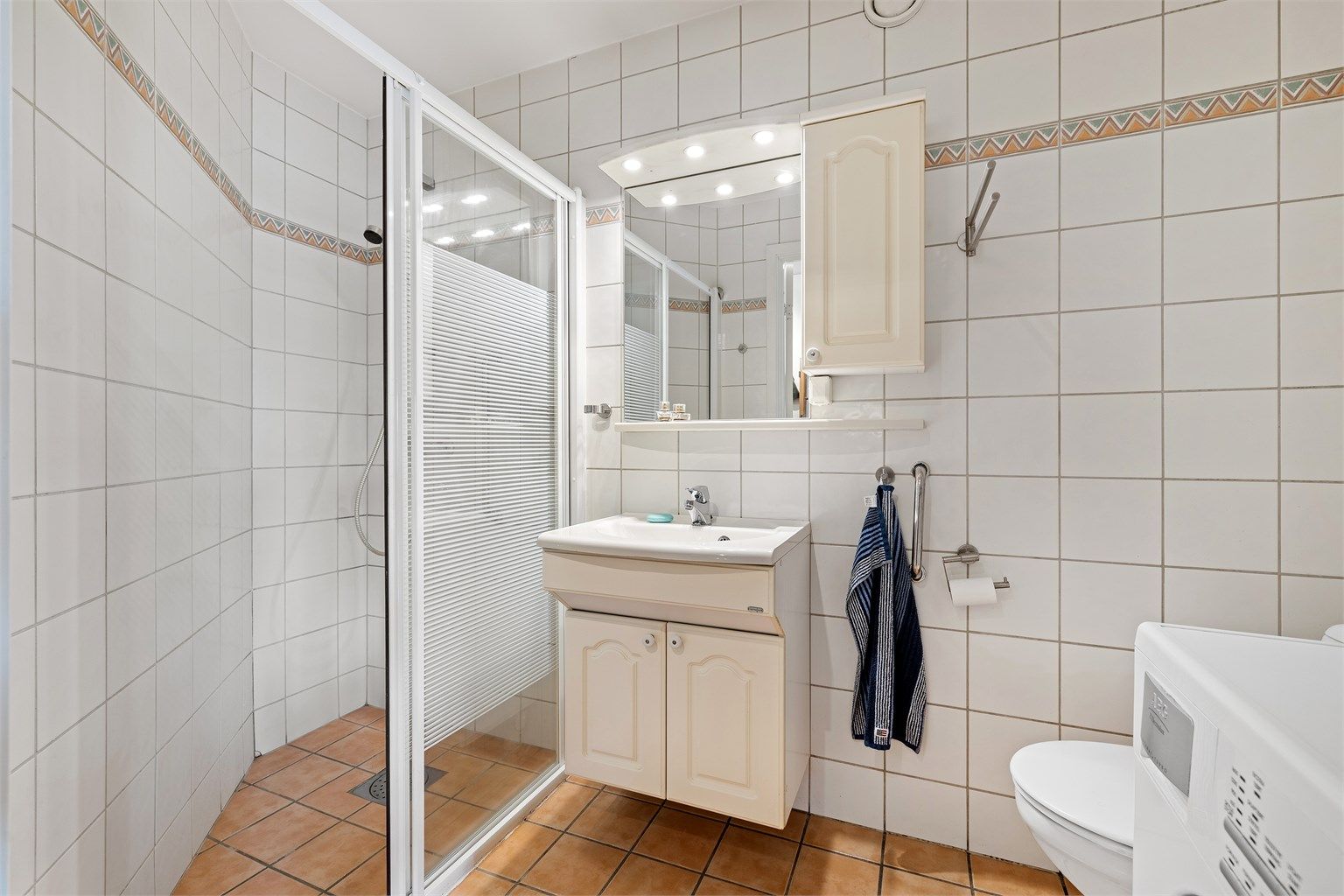 Leiligheten har to bad. Dette badet har dusjsone og opplegg for vaskemaskin.