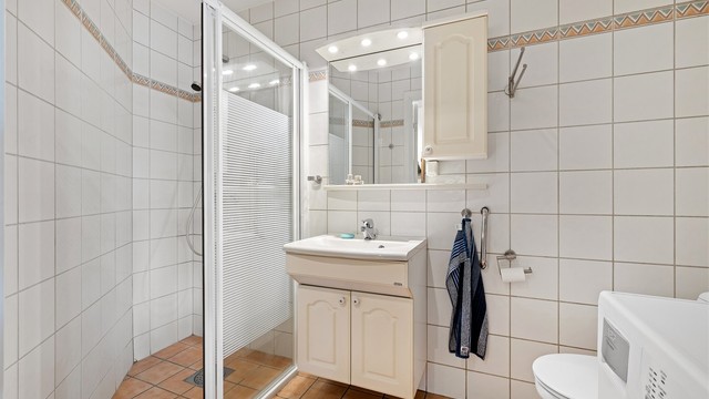 Leiligheten har to bad. Dette badet har dusjsone og opplegg for vaskemaskin.