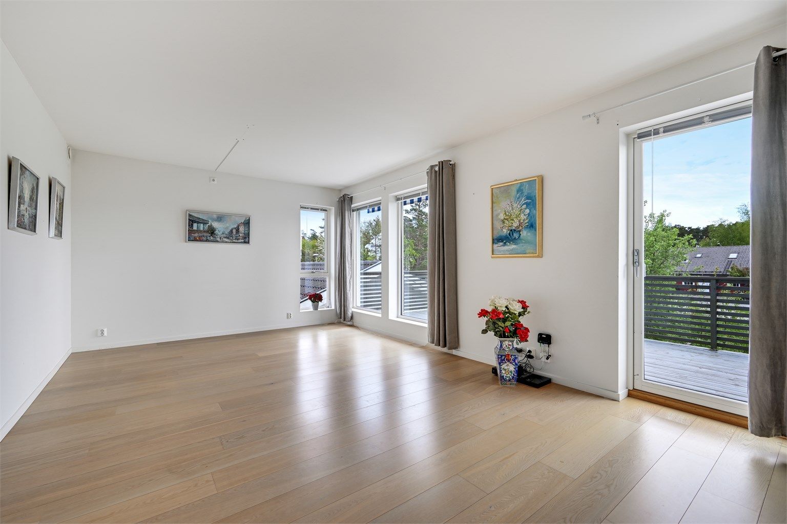 Stuen har god plass til både spisebord og sofagruppe, og store vindusflater gir rikelig med naturlig lys.