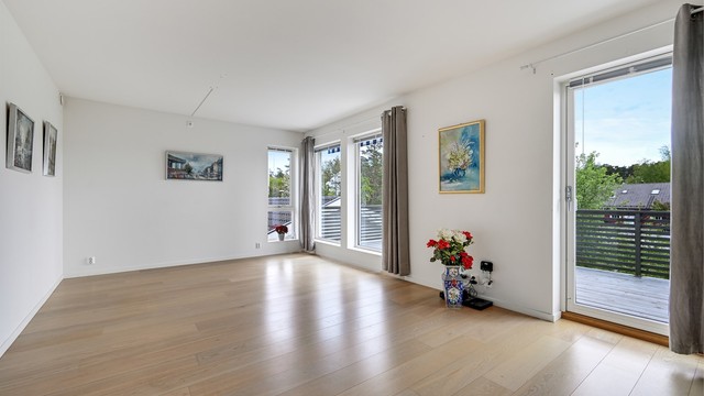 Stuen har god plass til både spisebord og sofagruppe, og store vindusflater gir rikelig med naturlig lys.
