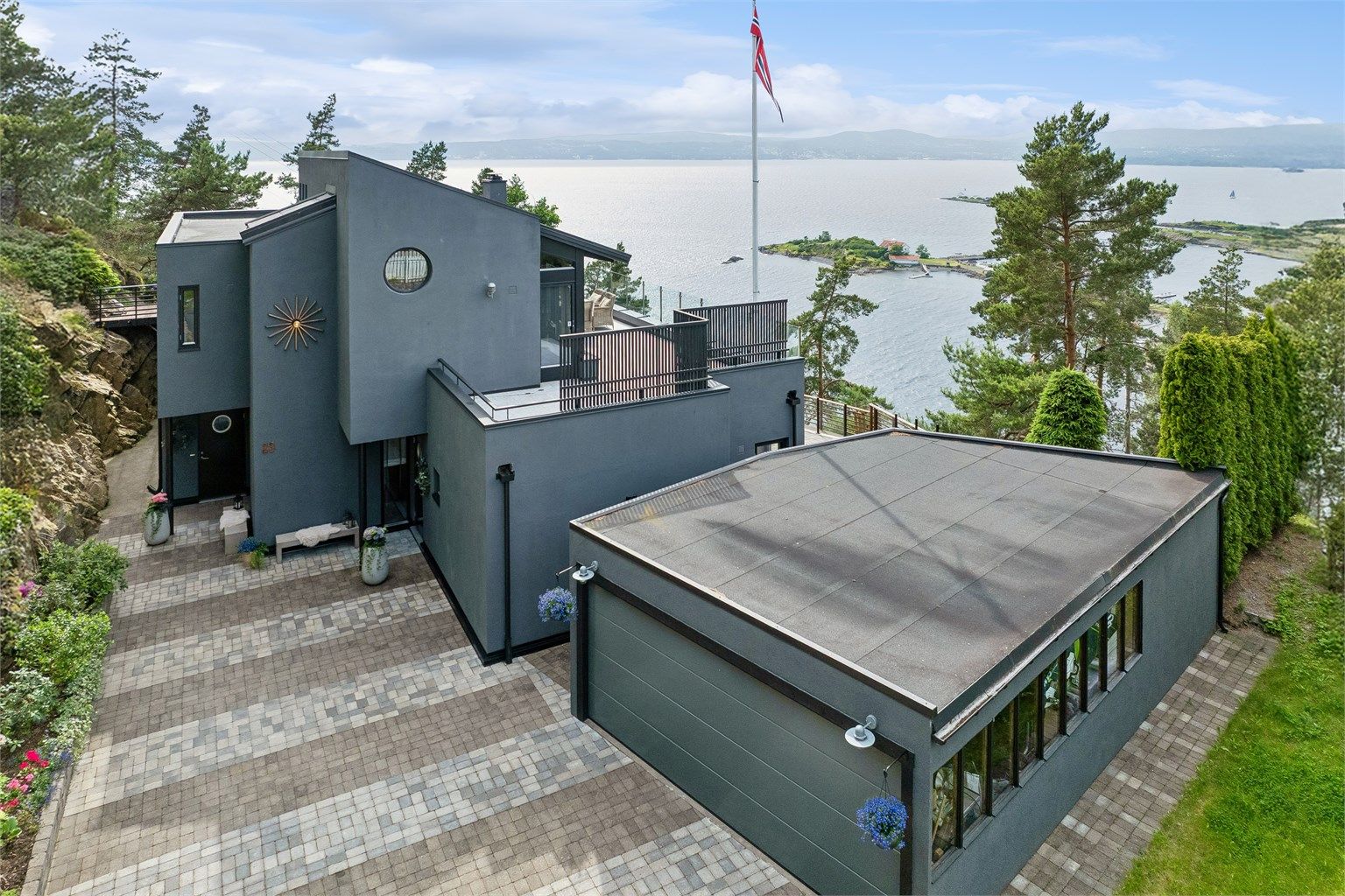 Pent opparbeidet tomt i skjønn forening med naturtomt. Brosteinslagt gårdsplass med god plass til parkering samt egen garasje.