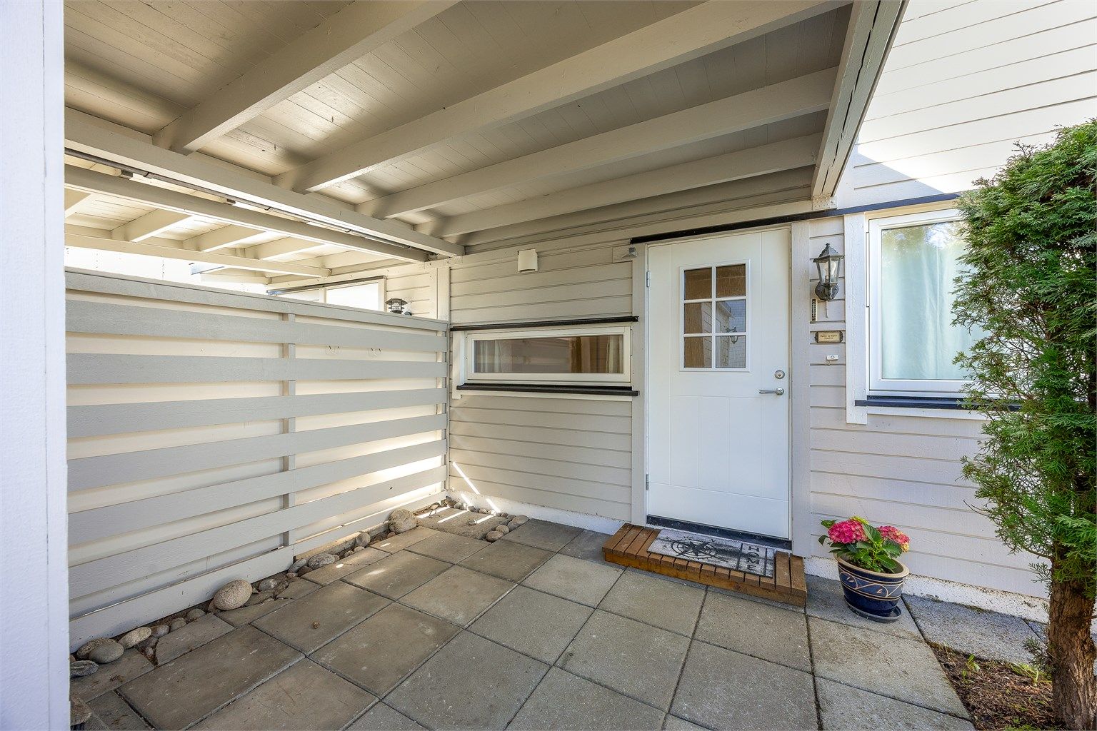 Overbygd inngangsparti som gir ly for vær og vind.