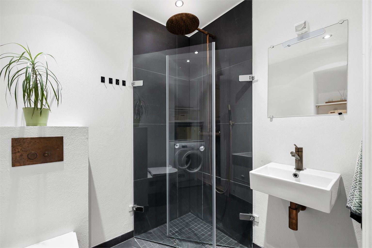 Rommet har en harmonisk kombinasjon av lyse, malte veggflater og gjennomførte bronsefargede detaljer, som sammen gir et moderne og elegant uttrykk.