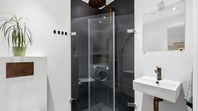 Rommet har en harmonisk kombinasjon av lyse, malte veggflater og gjennomførte bronsefargede detaljer, som sammen gir et moderne og elegant uttrykk.