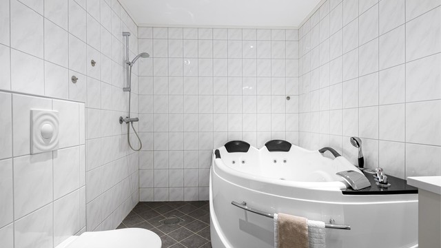 Baderommet er utstyrt med både separat dusj i hjørne og innbygget badekar.