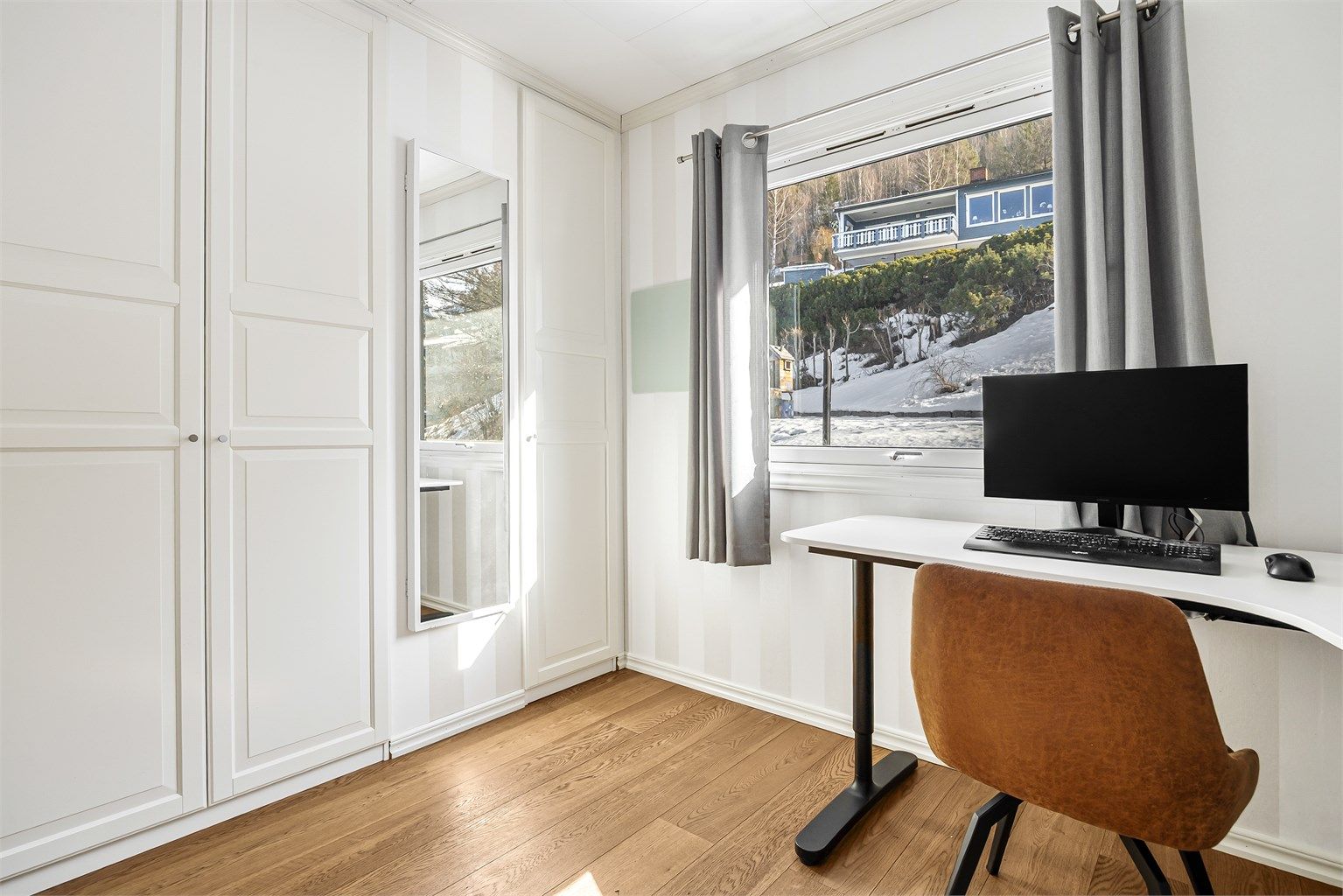 Det ene rommet i 1. etasje har en innebygget garderobeløsning med garderobeskap i hvit og profilert utførelse.