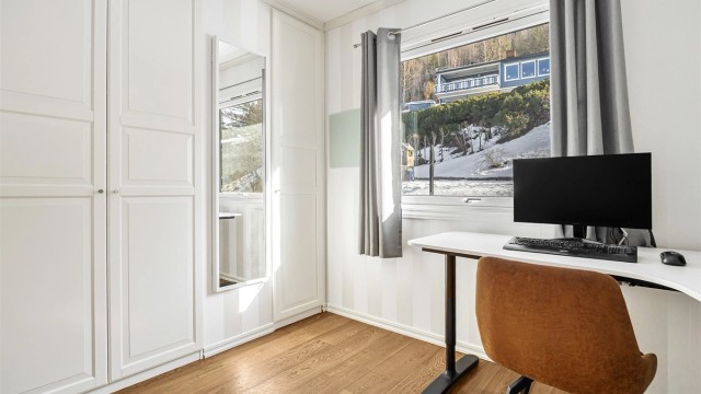 Det ene rommet i 1. etasje har en innebygget garderobeløsning med garderobeskap i hvit og profilert utførelse.