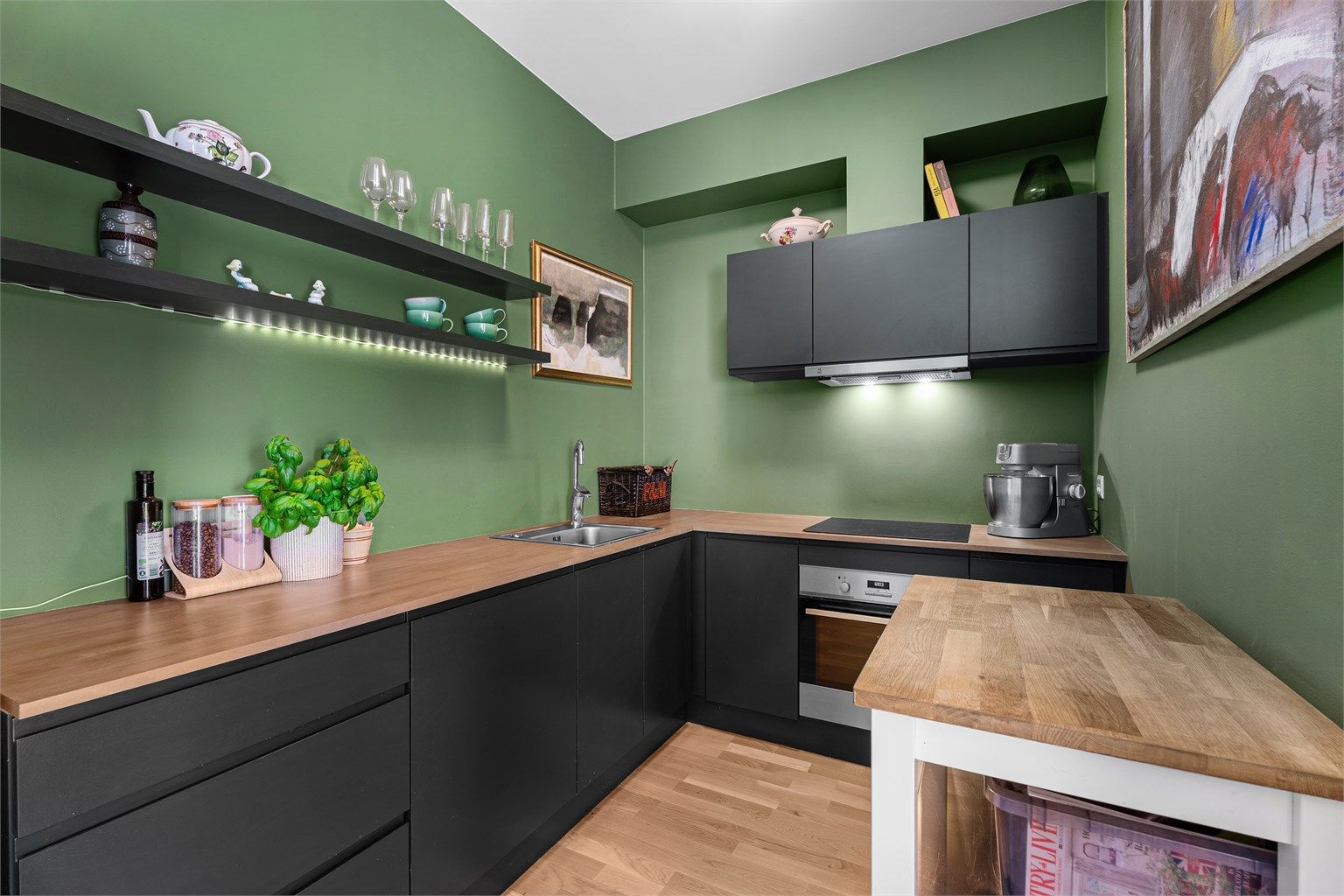 Moderne stilfult kjøkken med god benkeplass kombinert med åpne hyller, skuffer og overskap. Skap er malt i fargen Studio Green fra Farrow&Ball