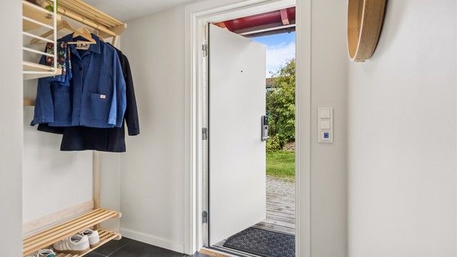 Lys og innbydende entré med praktisk, flislagt gulv og god plass til oppbevaring av klær og sko.