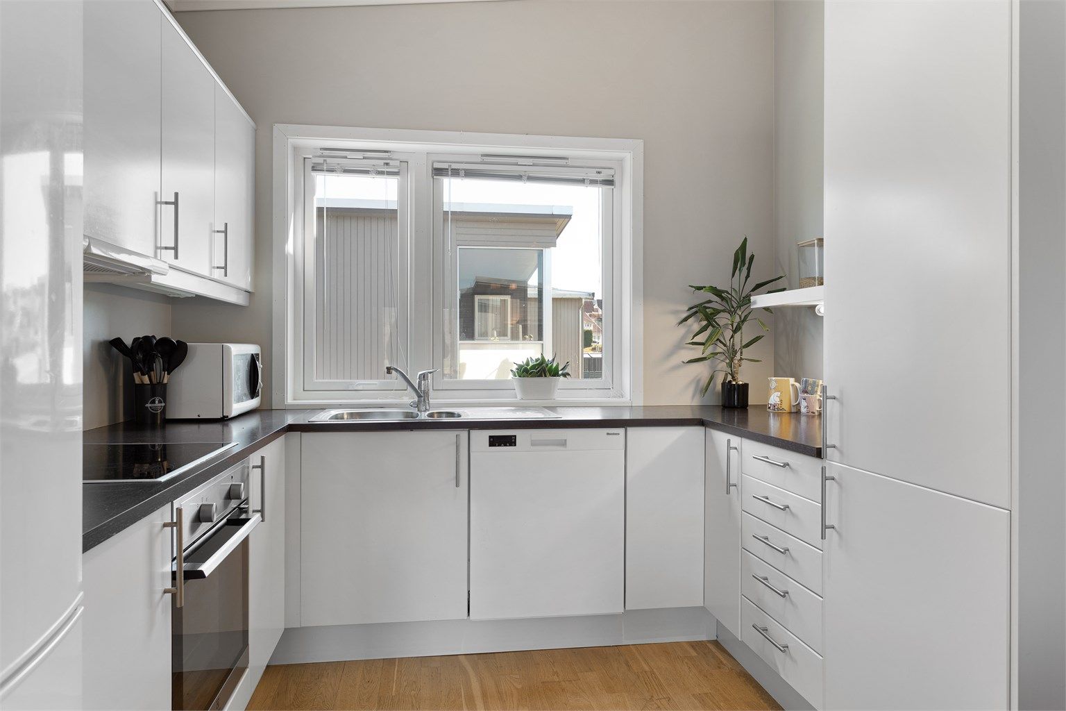 God arbeidsplass på kjøkkenbenken, med nedfelt vask og ventilator i overskapet.