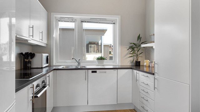 God arbeidsplass på kjøkkenbenken, med nedfelt vask og ventilator i overskapet.