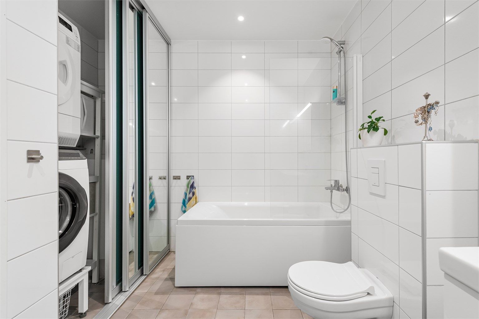 Badet fungerer også som vaskerom, med en smart løsning for vaskesøyle skjult bak skyvedører.