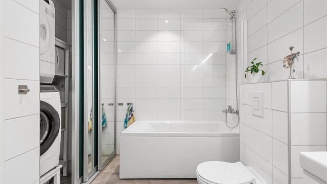 Badet fungerer også som vaskerom, med en smart løsning for vaskesøyle skjult bak skyvedører.