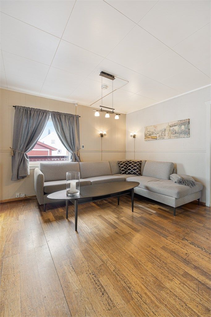 Rommet har gulvflater av parkett og laminat, og god plass til sofagruppe.