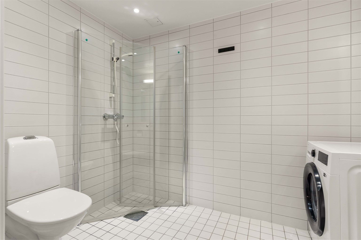 Badet er en prefabrikkert modul fra byggeåret, med vegghengt toalett og dusjhjørne med dører.