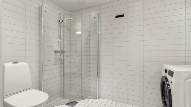 Badet er en prefabrikkert modul fra byggeåret, med vegghengt toalett og dusjhjørne med dører.