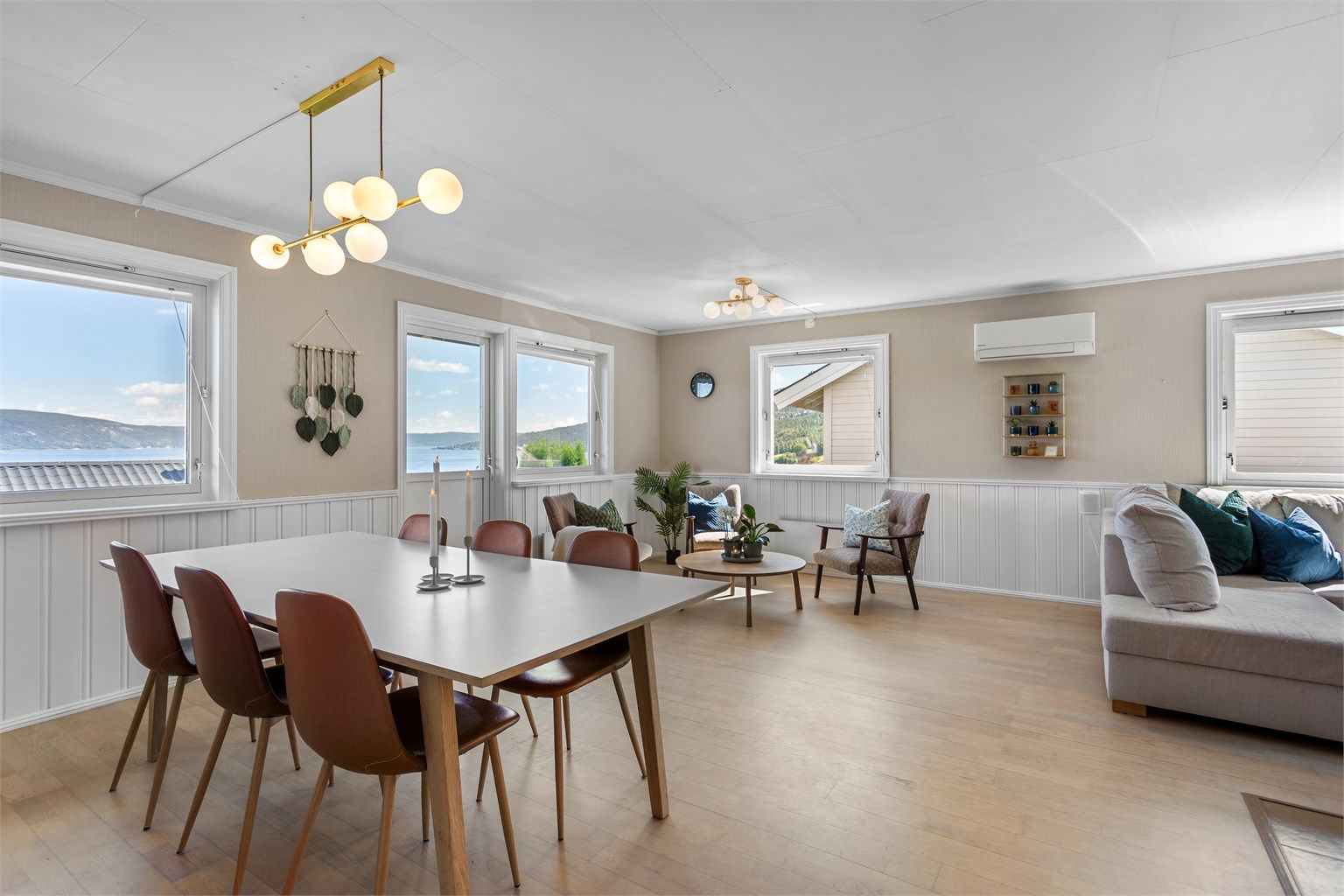 Lys og luftig vinkelstue med sofaområde, spiseplass samt sittegruppe