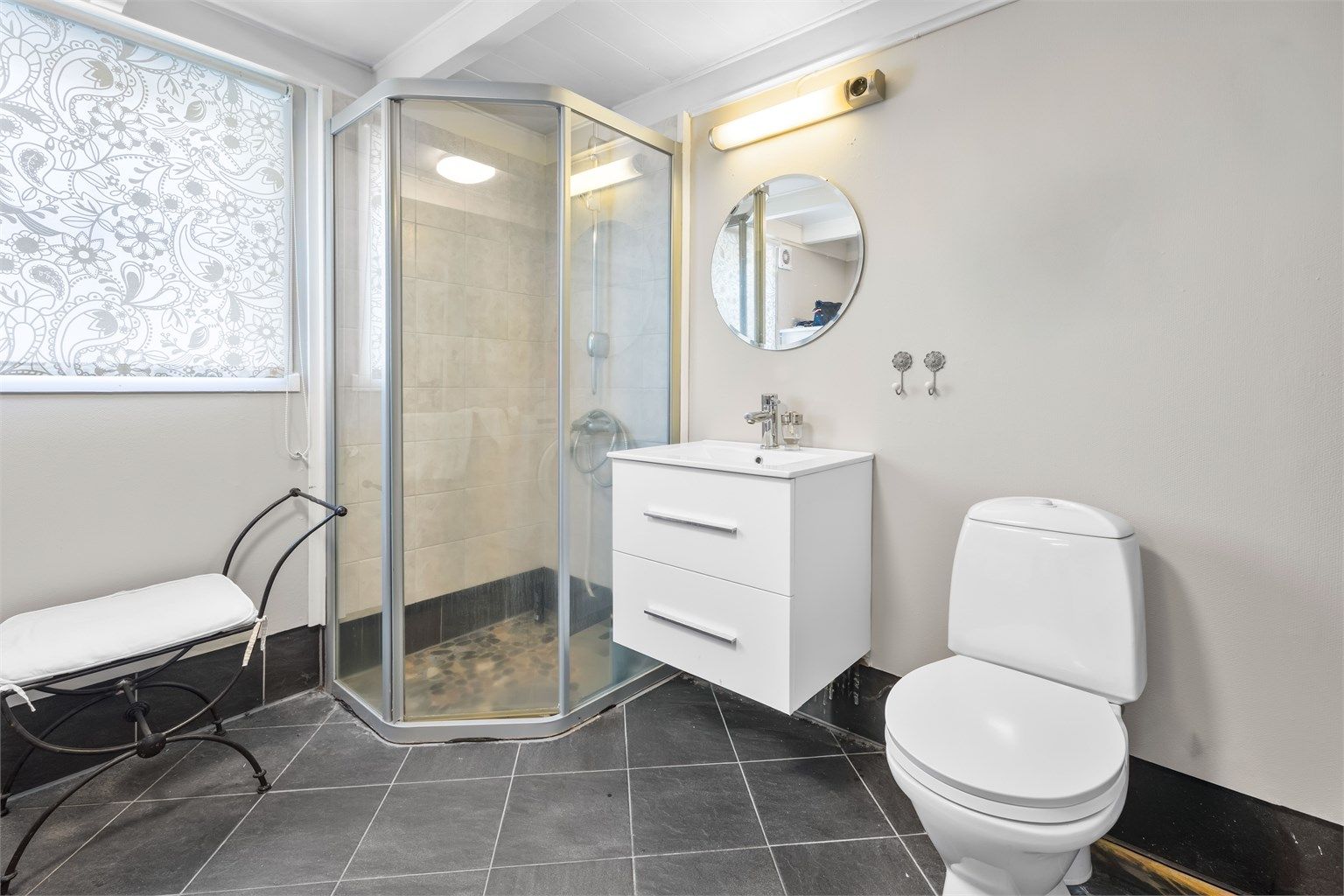 Badet i første etasje er utstyrt med toalett, servant og dusjkabinett.