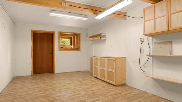 Det store hobbyrommet i kjelleren på 25 kvm har egen inngang og er innredet med vedovn, arbeidsbenk og oppbevaringsløsninger.