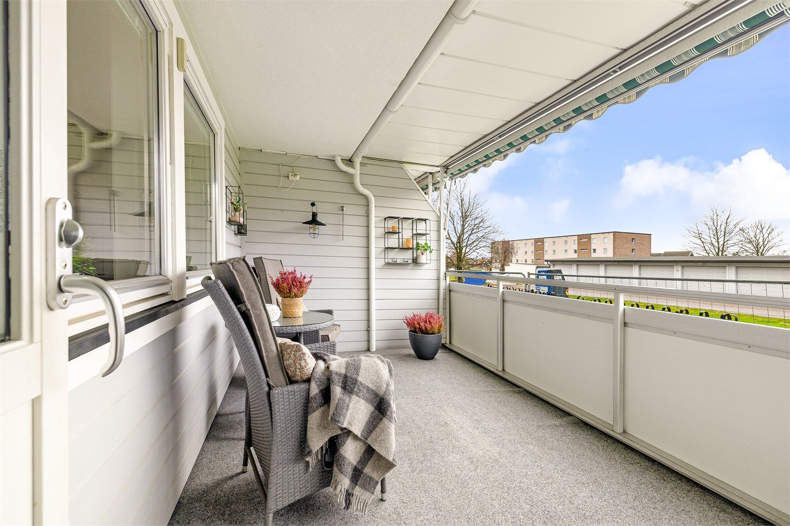 Romslig balkong med takoverbygg og markise, lun atmosfære og åpen utsyn mot nærliggende grøntområder.