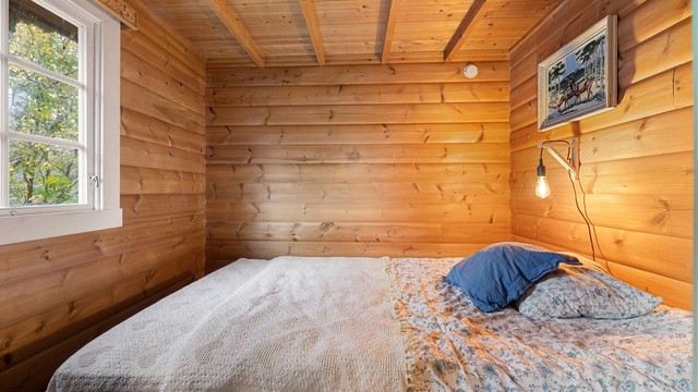 Soverom med heltre gulv og ubehandlet panel på vegger og i himling.