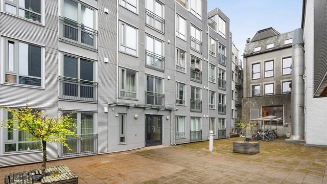 Felles atrium med sittebenker og beplantning. Uteområde med sykkelparkering og inngang til borettslagets oppganger.