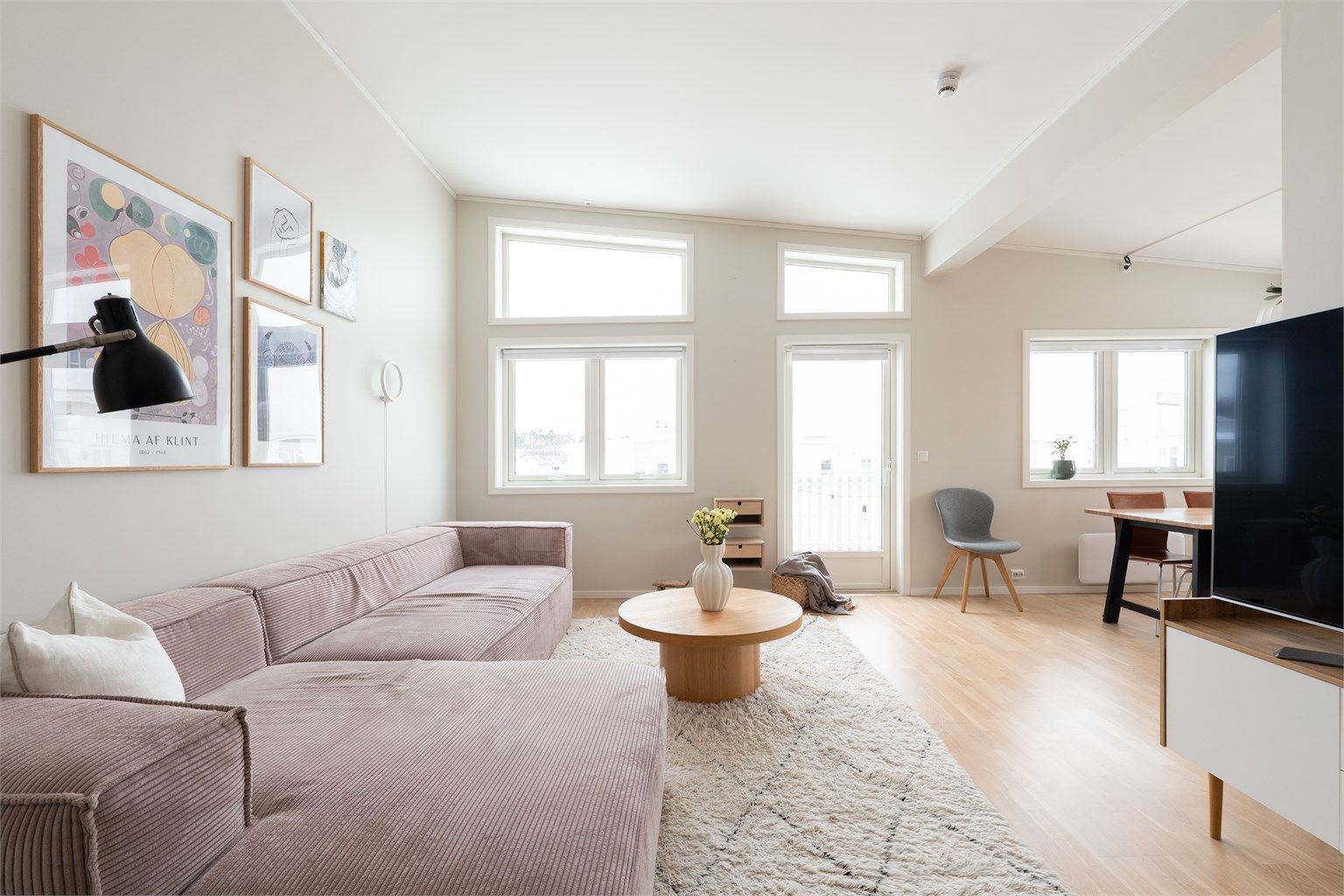 Åpen stue med generøst lysinnslipp, lys parkett og klare siktlinjer som framhever rommets areal og rolige utsyn.