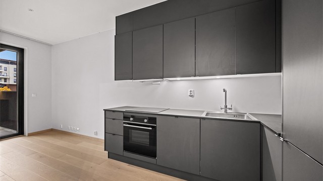 Stilrent kjøkken med glatte fronter og laminert benkeplate.
