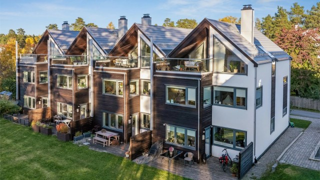 Kombinasjonen av mørk trekledning og hvite murflater gir bebyggelsen et tidløst og helhetlig uttrykk.