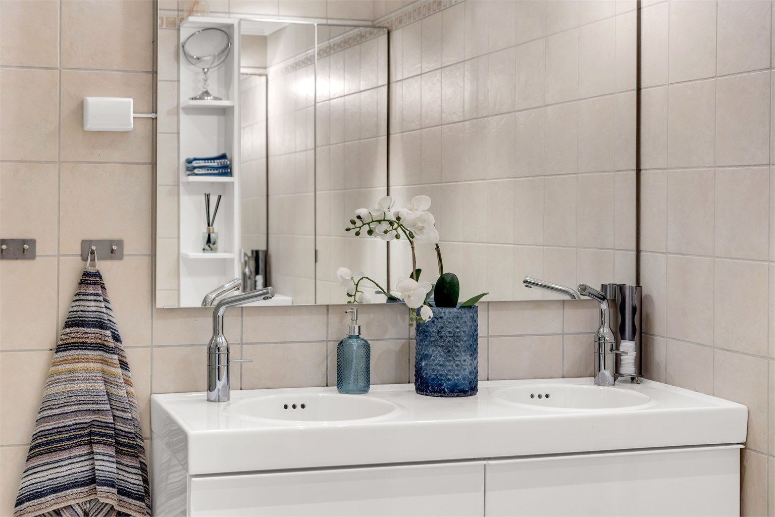 Badet har vegghengt servantinnredning, dobbel ovenpåliggende servant med armaturer, smat speil med sidelys og stikkontakt over servant. 