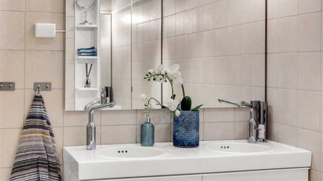 Badet har vegghengt servantinnredning, dobbel ovenpåliggende servant med armaturer, smat speil med sidelys og stikkontakt over servant.