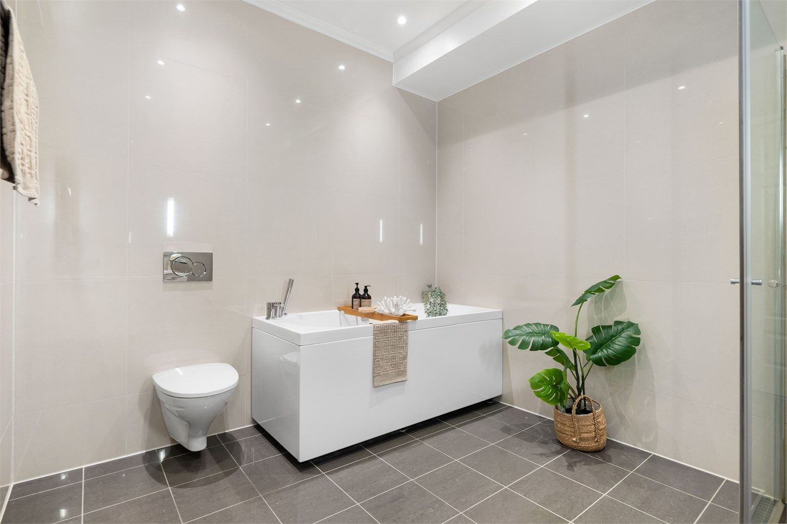 Badet er helfliset med gulvvarme og innredet med baderomsmøbler med dobbel vask, vegghengt wc og både dusjhjørne og badekar